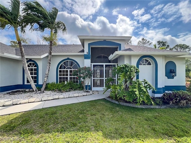 view of front facade featuring roof with shingles, a front lawn, and stucco siding