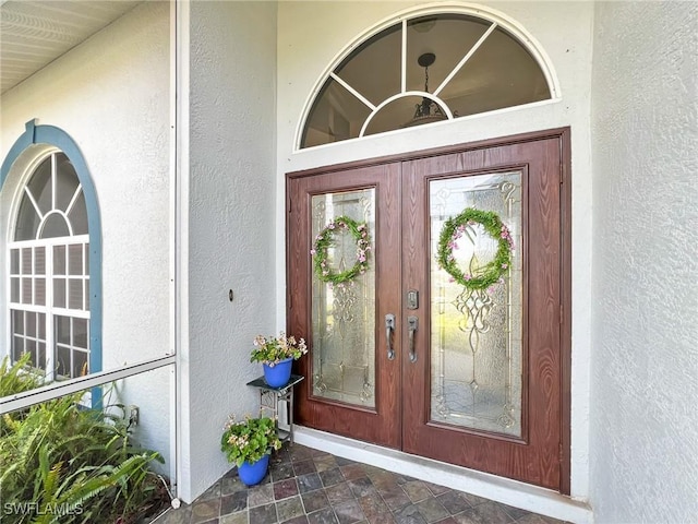 entrance to property featuring french doors and stucco siding