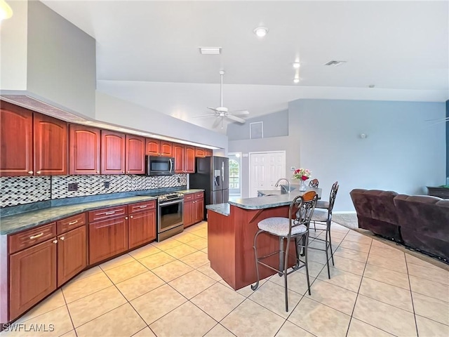 kitchen with light tile patterned floors, tasteful backsplash, stainless steel appliances, and a kitchen breakfast bar