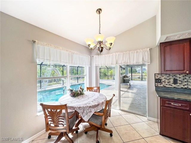 dining space featuring light tile patterned floors, vaulted ceiling, baseboards, and an inviting chandelier