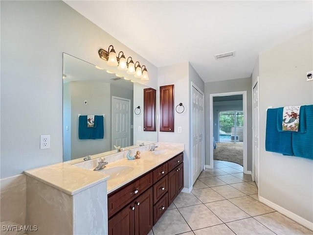 bathroom with double vanity, tile patterned flooring, a sink, and baseboards