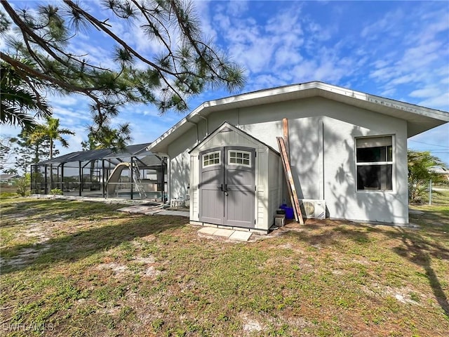 exterior space featuring glass enclosure, a shed, a lawn, and an outdoor structure