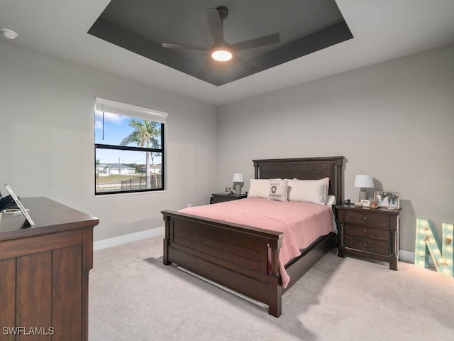 509 SW 8th Ct, Cape Coral, FL 33991 - bedroom featuring baseboards, light carpet, a tray ceiling, and a ceiling fan