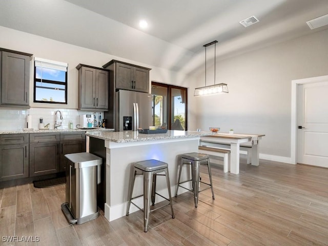 509 SW 8th Ct, Cape Coral, FL 33991 - kitchen featuring stainless steel fridge with ice dispenser, a sink, a kitchen bar, backsplash, and light wood-type flooring