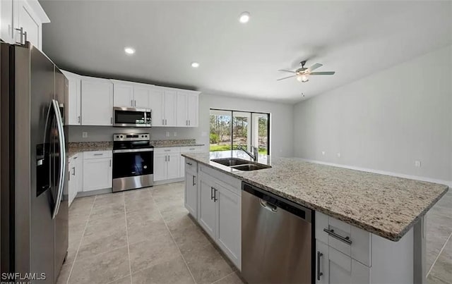 kitchen featuring stainless steel appliances, white cabinetry, a sink, and light stone countertops