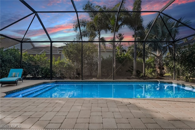 pool at dusk with a lanai, a patio area, and an outdoor pool