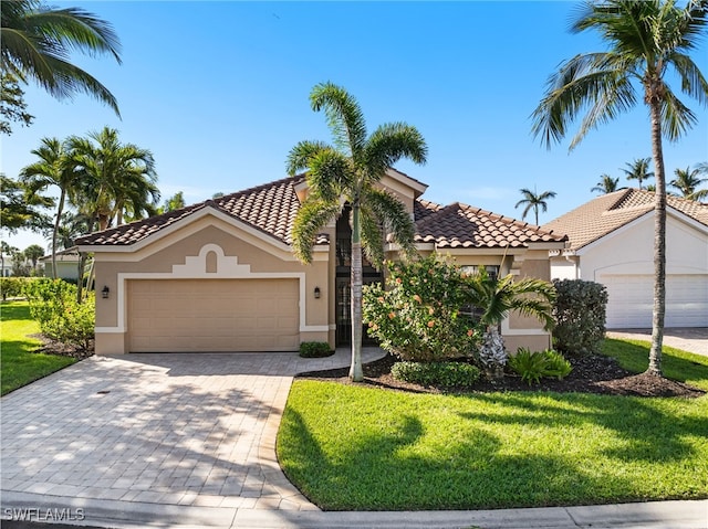 mediterranean / spanish home featuring a garage, a tiled roof, decorative driveway, and stucco siding