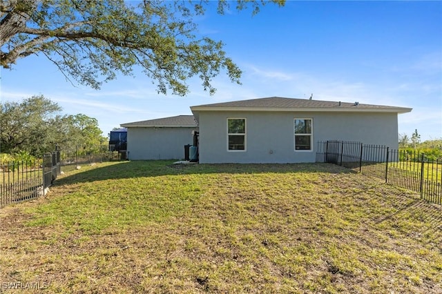 back of property featuring a fenced backyard, a lawn, and stucco siding