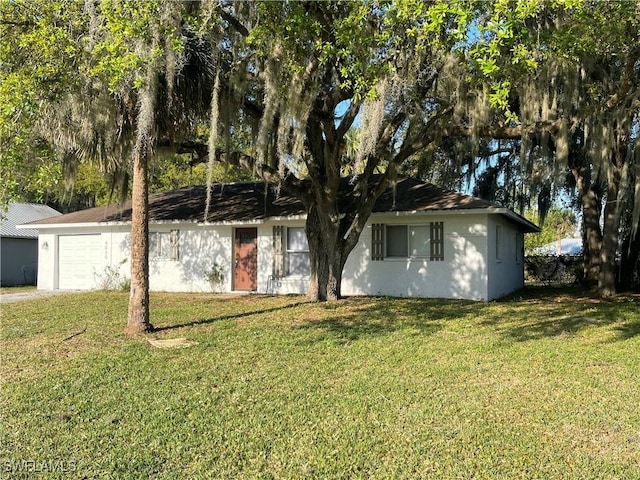 ranch-style home with a garage, a front yard, and stucco siding