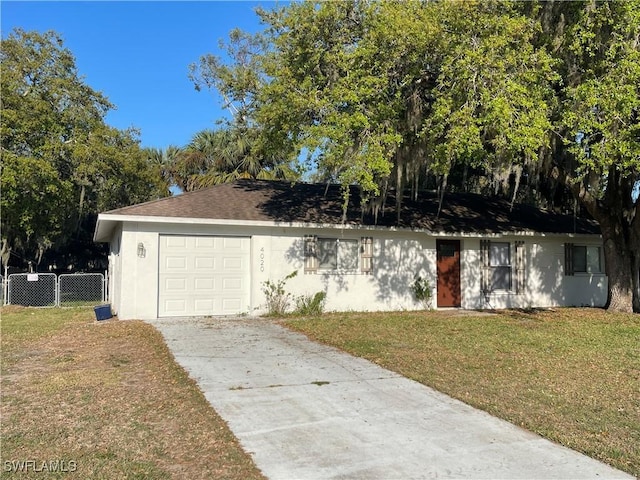 view of front facade with stucco siding, concrete driveway, a front yard, fence, and a garage