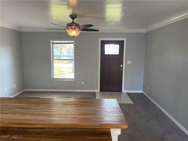 tiled foyer entrance with ceiling fan, ornamental molding, and baseboards