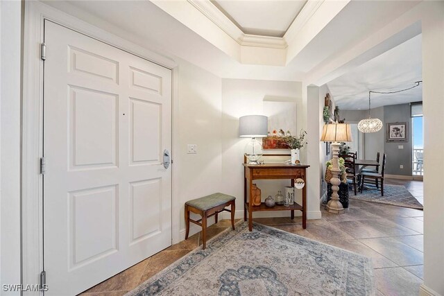 entryway featuring baseboards, a chandelier, and crown molding