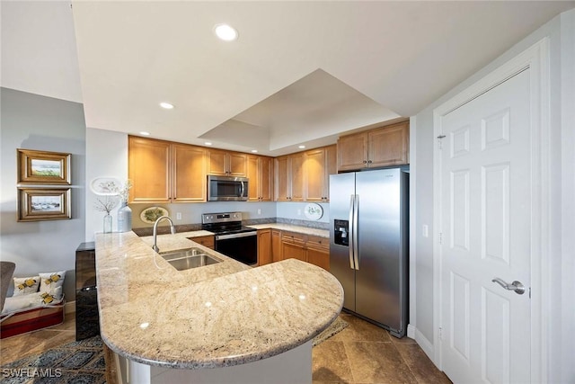 kitchen with light stone counters, recessed lighting, appliances with stainless steel finishes, a sink, and a peninsula