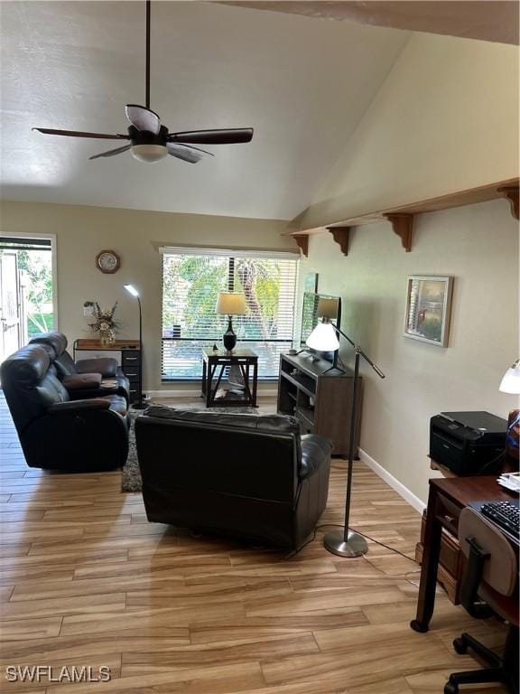 living room featuring ceiling fan, light wood-style flooring, high vaulted ceiling, and baseboards