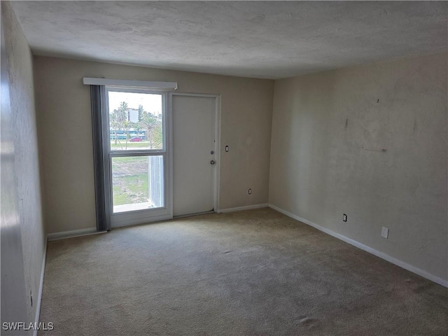 carpeted spare room with baseboards and a textured ceiling