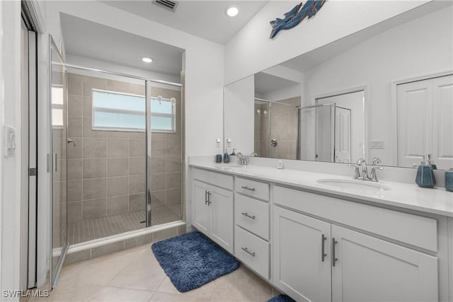 bathroom featuring tile patterned floors, double vanity, a stall shower, and a sink