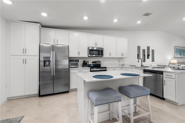 kitchen featuring visible vents, a peninsula, a sink, appliances with stainless steel finishes, and white cabinetry