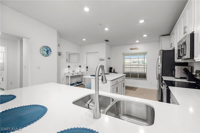 kitchen featuring white cabinetry, stainless steel appliances, light countertops, and a sink