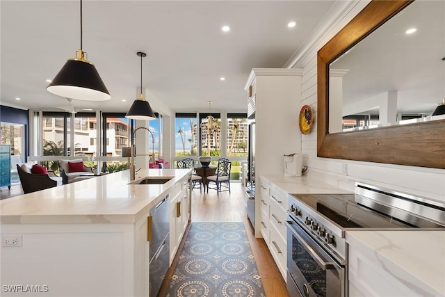 kitchen featuring appliances with stainless steel finishes, a sink, white cabinetry, and light wood-style floors