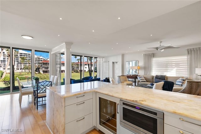 kitchen featuring open floor plan, stainless steel microwave, beverage cooler, and a healthy amount of sunlight