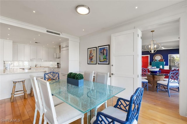 dining space with a notable chandelier, crown molding, visible vents, and light wood-style floors