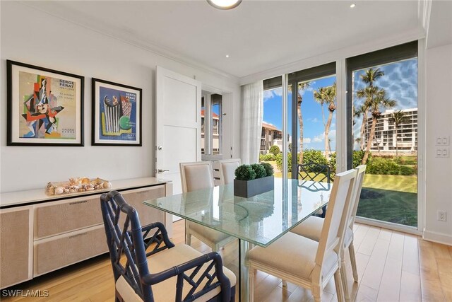 dining area with light wood-style floors, floor to ceiling windows, and crown molding