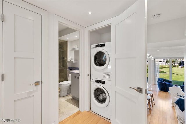 laundry room with stacked washer and dryer, light wood finished floors, and recessed lighting