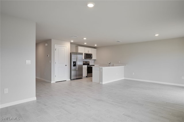 unfurnished living room with light wood-style floors, recessed lighting, a sink, and baseboards