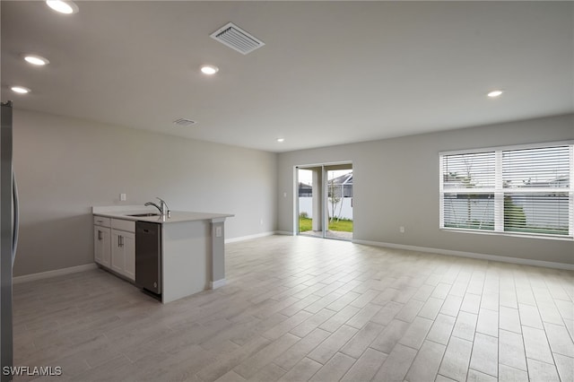 kitchen featuring visible vents, light wood-style flooring, open floor plan, a sink, and dishwasher