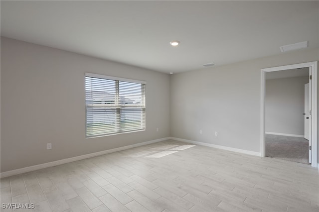 spare room featuring light wood-style floors, visible vents, and baseboards