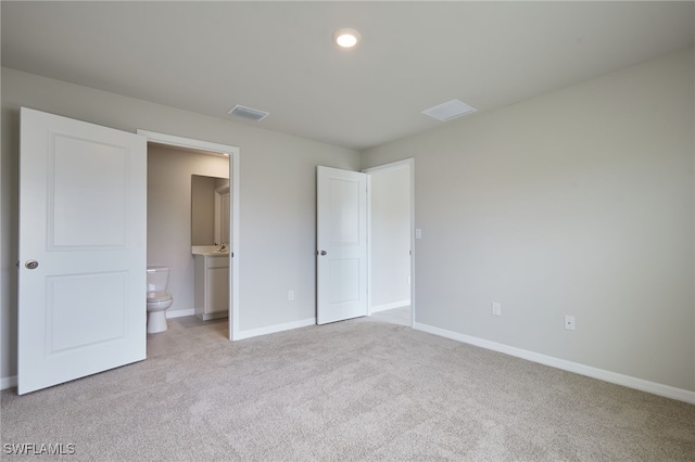 unfurnished bedroom featuring baseboards, connected bathroom, visible vents, and light colored carpet