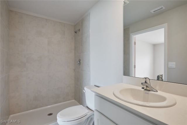 full bathroom featuring toilet, visible vents, a tile shower, and vanity