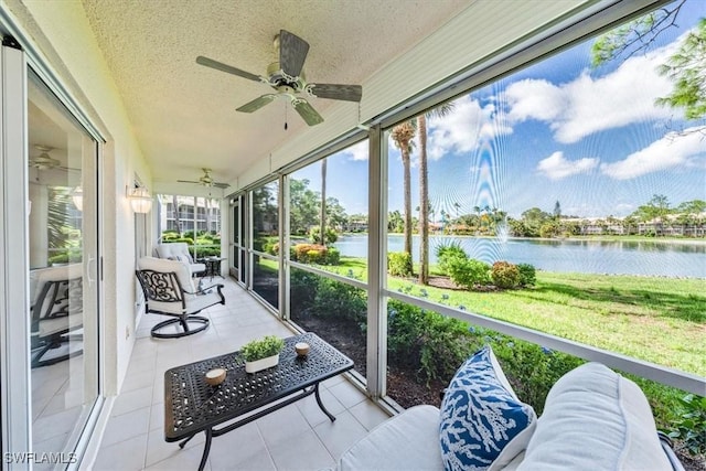 sunroom featuring a water view and a ceiling fan