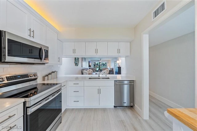 kitchen with visible vents, stainless steel appliances, a sink, and light countertops