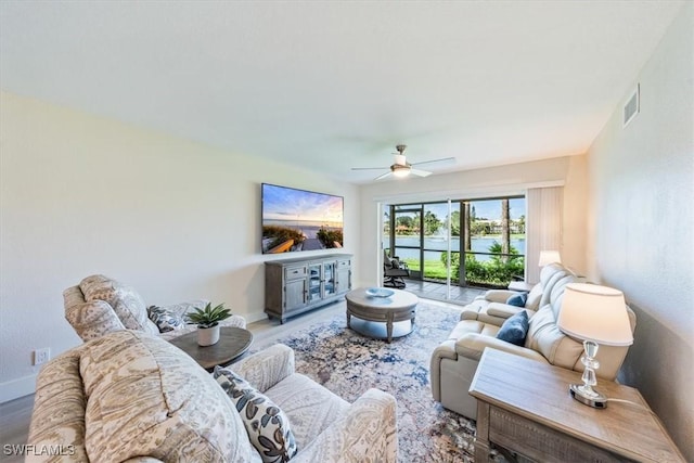 living area with ceiling fan, wood finished floors, visible vents, and baseboards