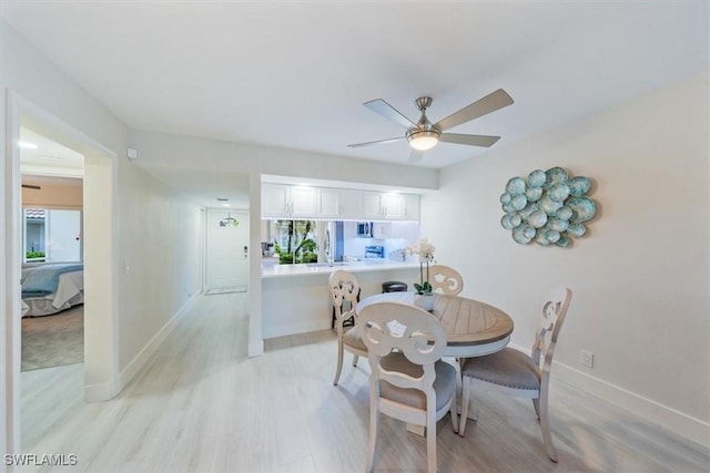 dining space with light wood-type flooring, ceiling fan, and baseboards