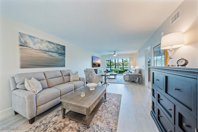 living room featuring light wood-style floors, visible vents, ceiling fan, and baseboards