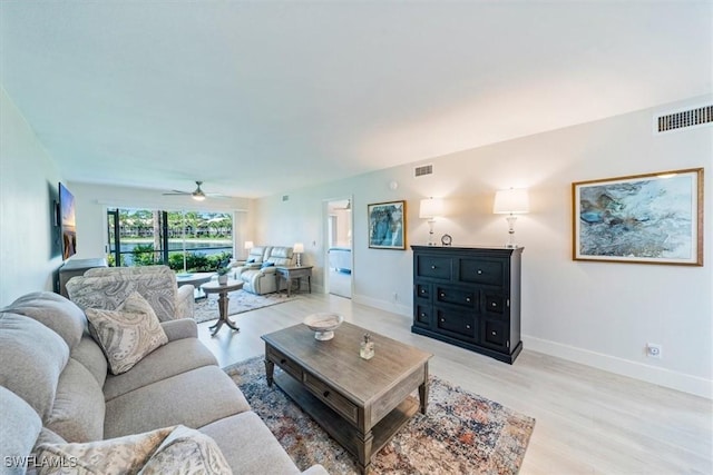 living room featuring light wood-style flooring, visible vents, ceiling fan, and baseboards