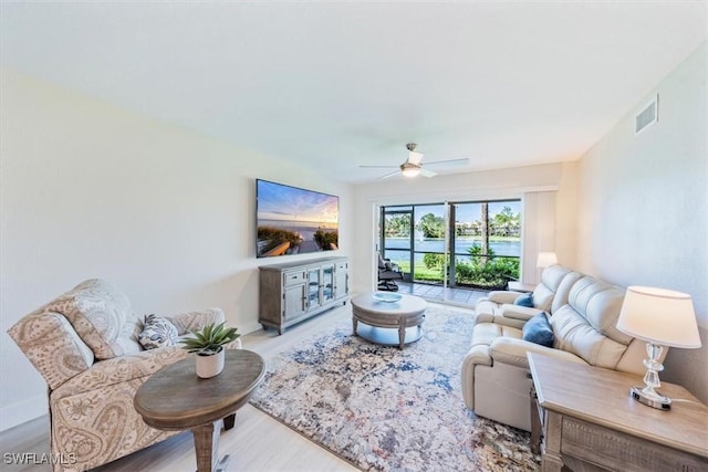 living area featuring baseboards, wood finished floors, visible vents, and a ceiling fan
