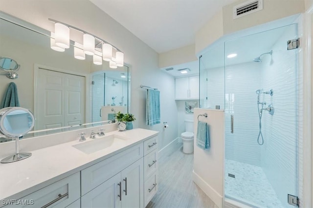 bathroom featuring a stall shower, baseboards, visible vents, toilet, and vanity