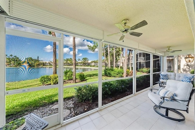 sunroom featuring a ceiling fan and a water view