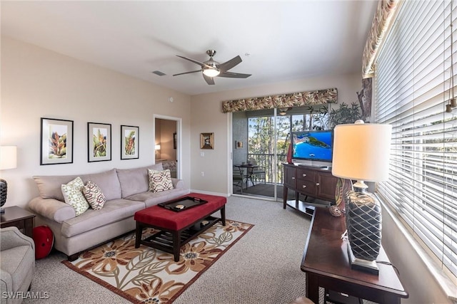 living area featuring baseboards, visible vents, a ceiling fan, and carpet