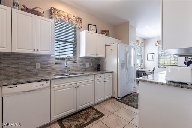 kitchen featuring white appliances, white cabinets, tasteful backsplash, and a sink