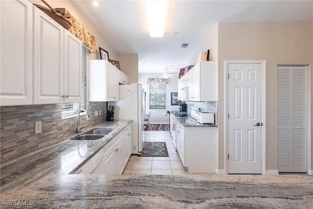 kitchen featuring visible vents, light tile patterned flooring, white cabinets, white appliances, and a sink