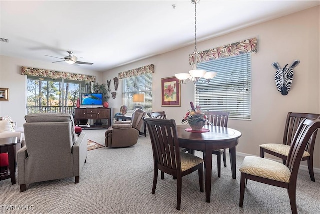 carpeted dining space with visible vents, baseboards, and ceiling fan with notable chandelier