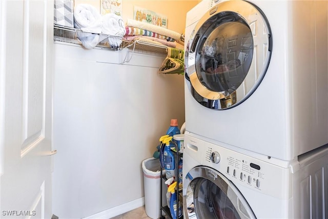 clothes washing area with stacked washer / drying machine, baseboards, and laundry area