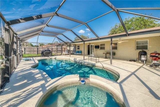 view of swimming pool featuring fence, a pool with connected hot tub, ceiling fan, a lanai, and a patio area