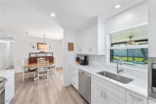 kitchen featuring ceiling fan, light wood-type flooring, stainless steel dishwasher, white cabinets, and a sink