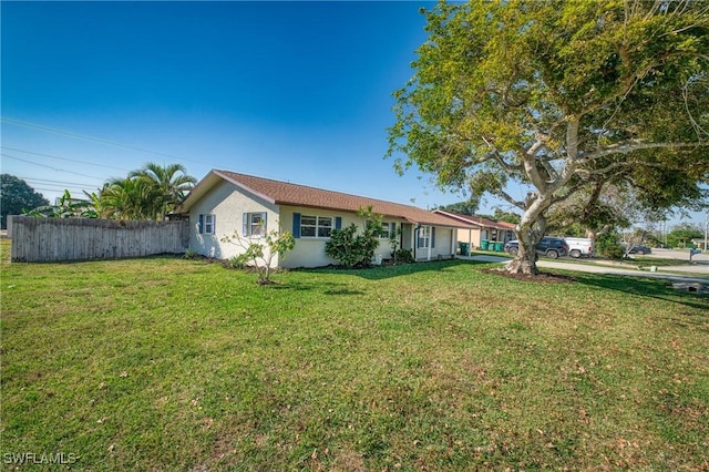 view of front of home featuring stucco siding, a front lawn, and fence