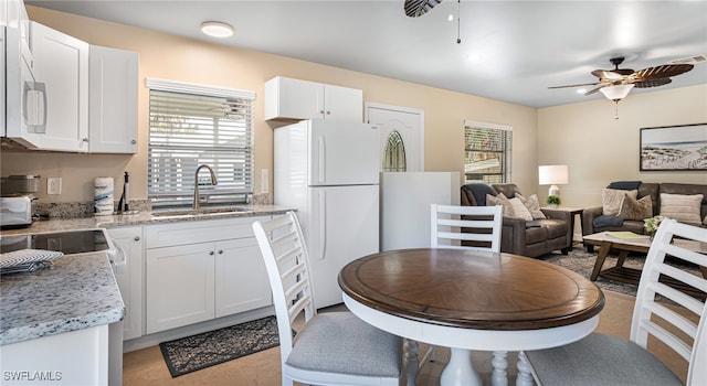 kitchen featuring white appliances, white cabinetry, a ceiling fan, and a sink